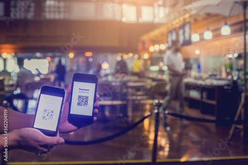 Selective focus to smart phone in hand to scan QR code on tag with blurry customer is buying food in restaurants to accepted generate digital pay without money. Qr code payment concept.