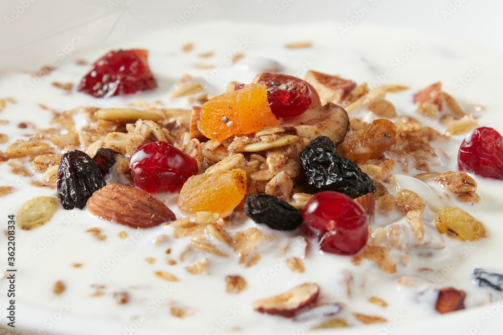 Granola (myusli) for breakfast with oatmeal, various seeds and dried fruits in a plate with milk close-up. Healthy and delicious diet breakfast. Granola (myusli) for breakfast with oatmeal, various seeds and dried fruits in a plate with milk close-up. Healthy and delicious diet breakfast.