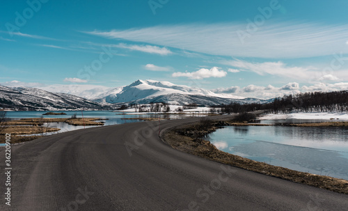 Road crossing beautiful nature reserve. Amazing snowy mountains landscape on Senja island, northern Norway. 