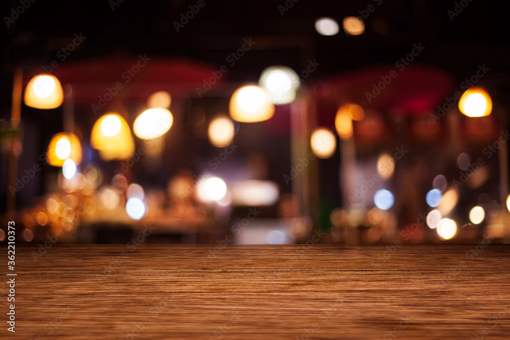 background Image of wooden table in front of abstract blurred restaurant lights. background Image of wooden table in front of abstract blurred restaurant lights.