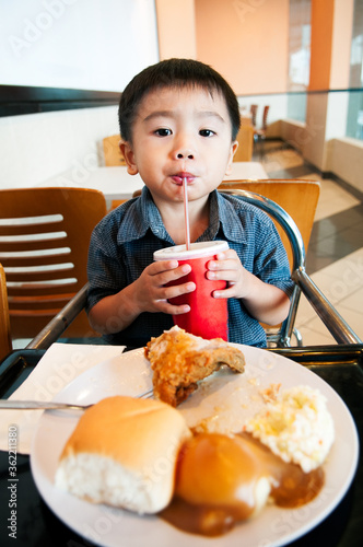 Little boy drinking soft drink in a cafe.