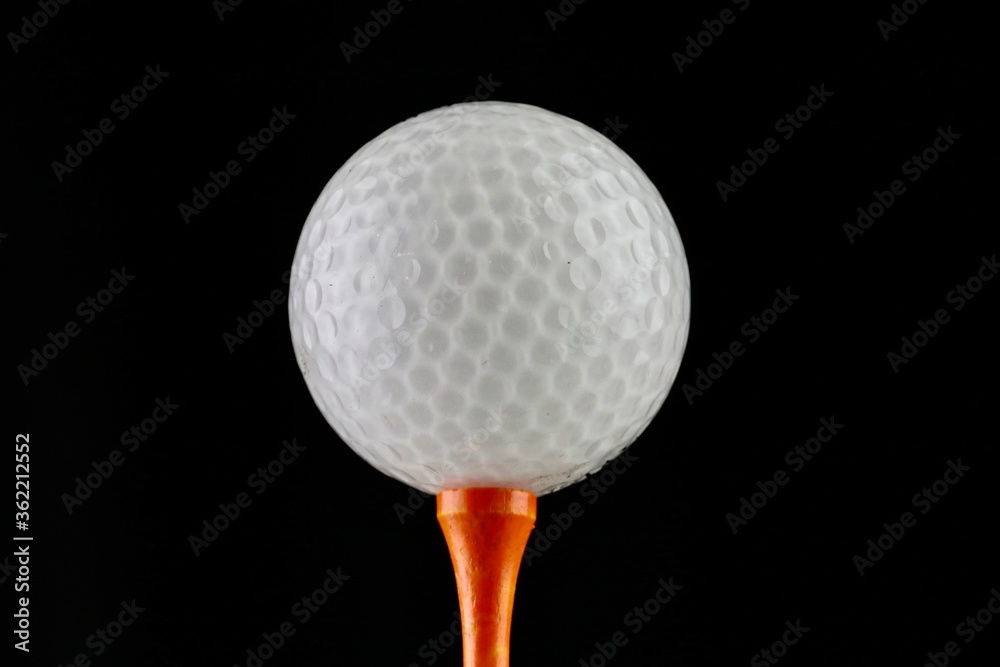 Golf ball and tee on a black background Golf ball and tee on a black background