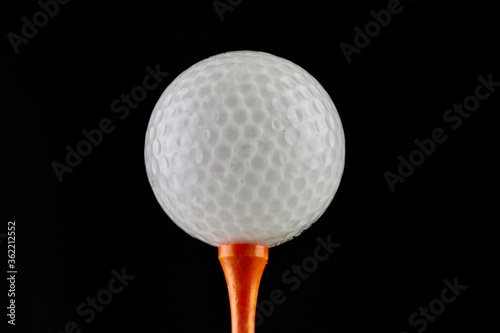 Golf ball and tee on a black background 
