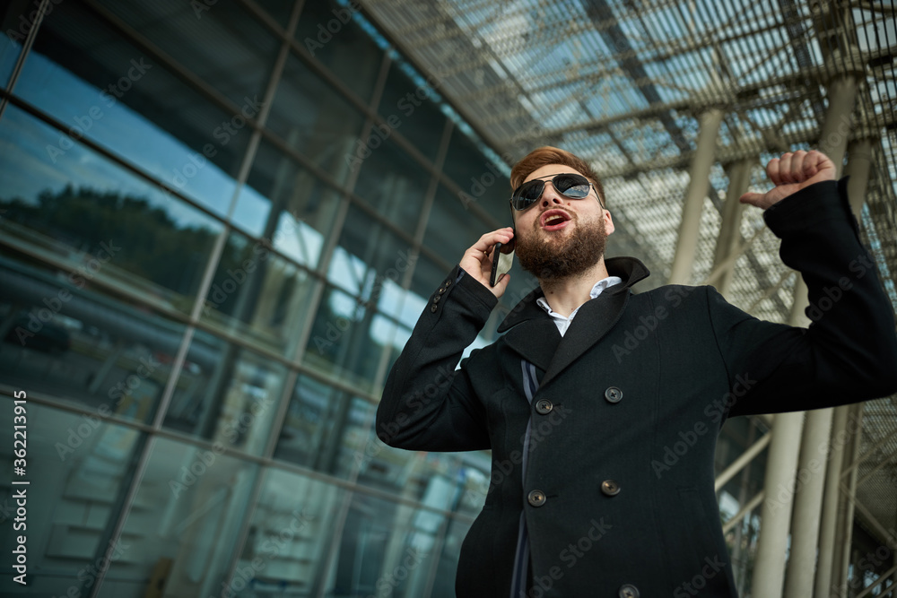 Urban business man in sunglasses talking smart phone traveling walking outside airport. Casual young businessman wearing suit jacket. Handsome male model in 20s, Manager, City Hall, cell. Urban business man in sunglasses talking smart phone traveling walking outside airport. Casual young businessman wearing suit jacket. Handsome male model in 20s, Manager, City Hall, cell.
