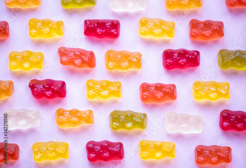 Sweet fruit gummy bears on pink background. Orange, red and yellow marmalade bears. Candy colorful pattern. Minimal design, flat lay, top view.