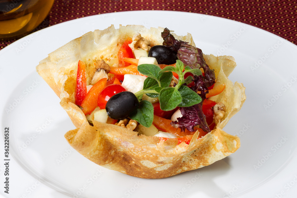 Vegetable salad with feta cheese, olives and nuts inside the pancake on white bowl. As backdrop for menus, cookbooks, advertisements and other culinary projects Vegetable salad with feta cheese, olives and nuts inside the pancake on white bowl. As backdrop for menus, cookbooks, advertisements and other culinary projects