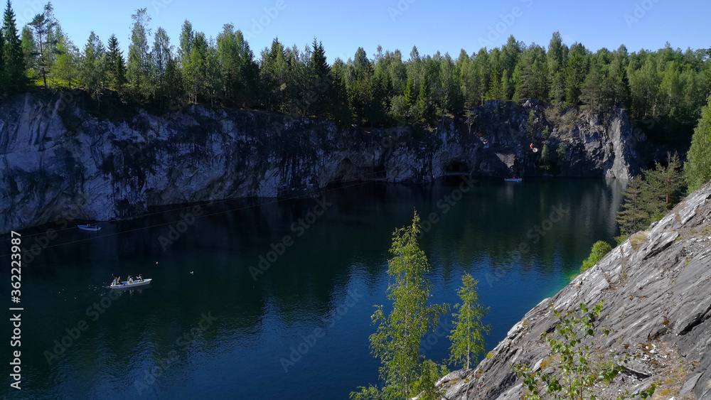 Tourist complex Karelia. Sunny summer day in the Marble Canyon. View of the flooded quarry with turquoise water.