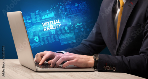 Businessman working on laptop with VIRTUAL REALITY inscription, cyber technology concept