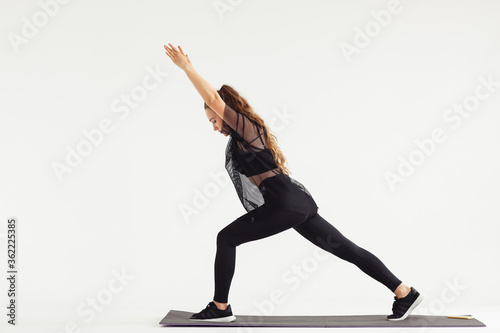 Slim girl practicing yoga isolated on white background. , Warrior 1 posture, Virabhadrasana. Concept of healthy life and natural balance between body and mental development.