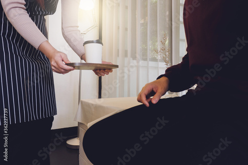 close up image of a waitress serving coffee to a customer in a cafe.