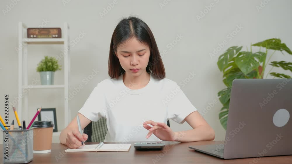 Woman using calculator to calculate income expenses and plans for spending money on home office.