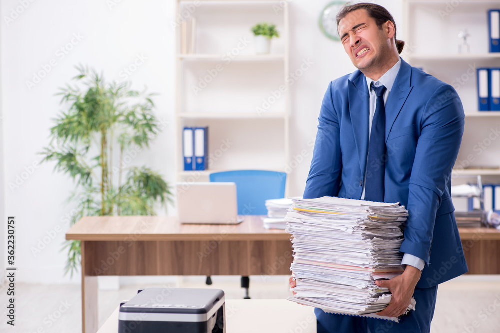Young male employee making copies at copying machine