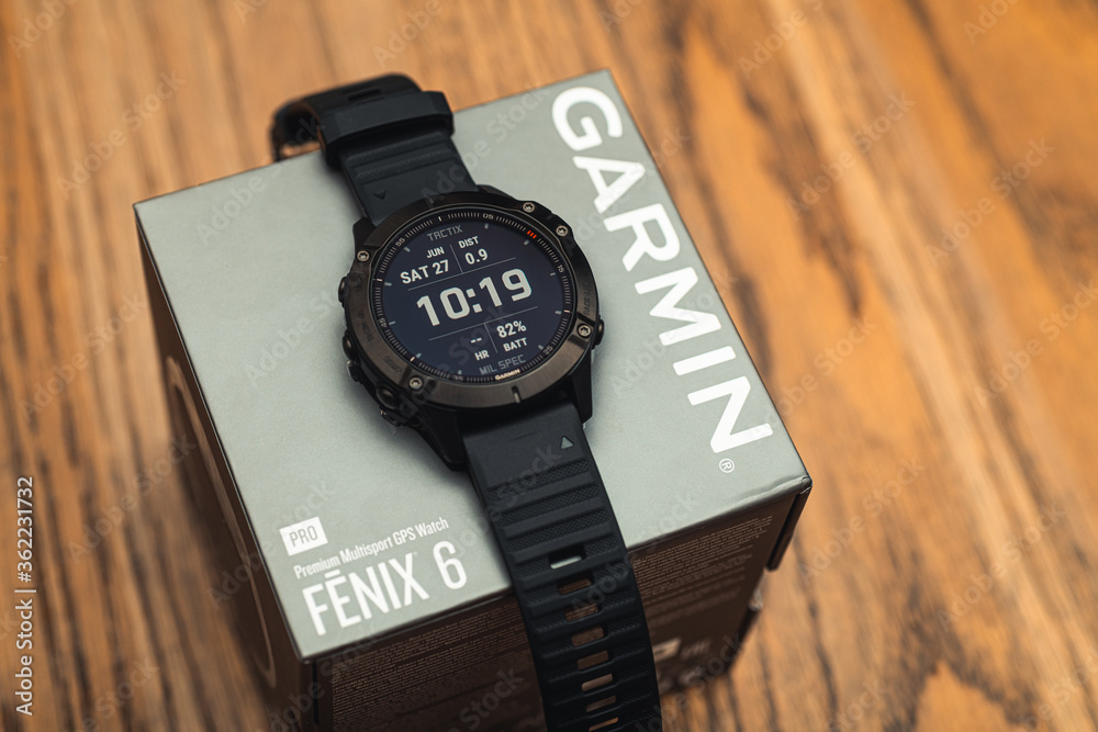 Foto Stock Garmin Fenix 6 Pro smart watch on box on wooden background.  Unpacking purchase concept | Adobe Stock