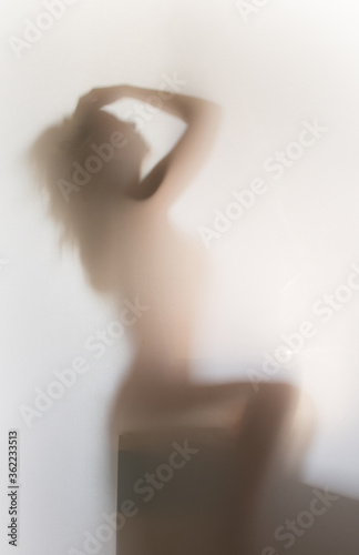 Sexy and mysterious sitting woman body and long hair shape silhouette can be seen behind a curtain.