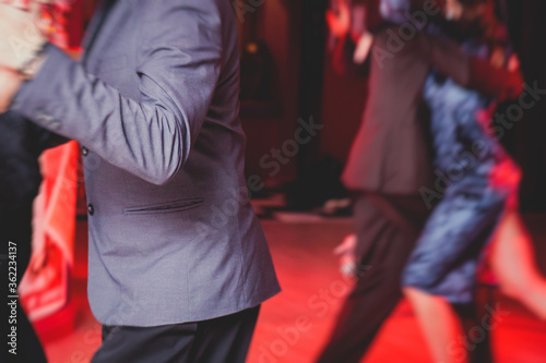 Couples dancing argentinian dance milonga in the ballroom, tango lesson in the red lights, dance festival