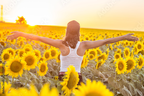 Girl meets the sunrise in a sunflower field.
