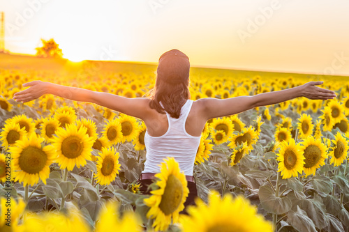 Girl meets the sunrise in a sunflower field.