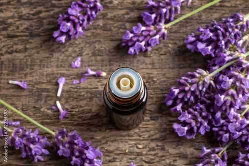 A dark bottle of essential oil with blooming lavender
