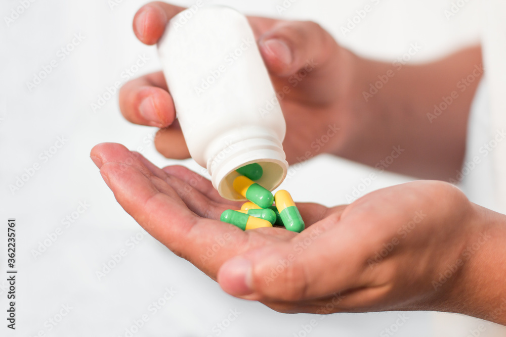 Pouring capsules from a pill bottle into hand Pouring capsules from a pill bottle into hand