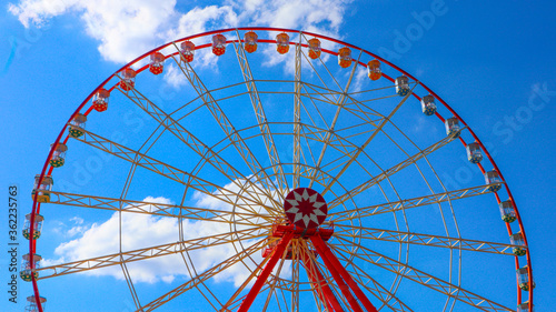 Ferris wheel on a sunny day in the park on a background of blue sky