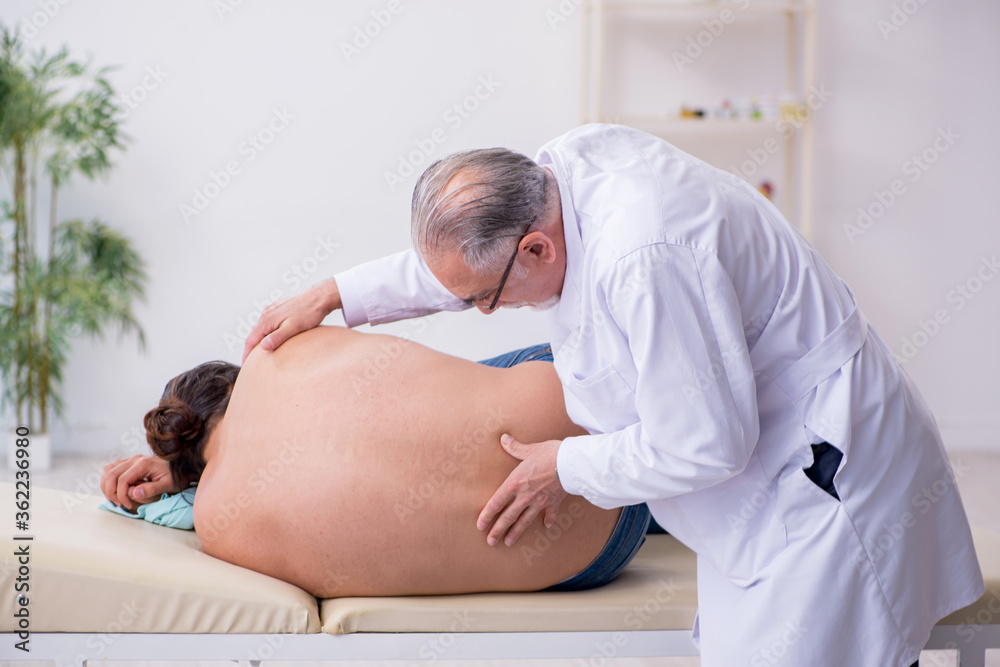 Fototapeta premium Young back injured man visiting experienced male doctor
