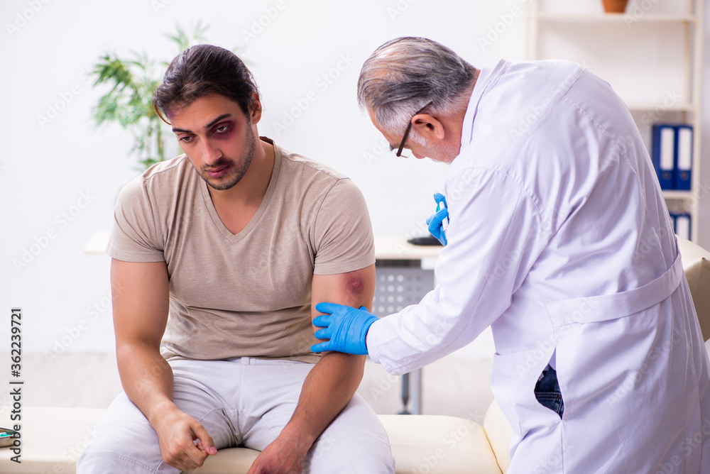 Fototapeta premium Young face injured man visiting experienced male doctor traumato