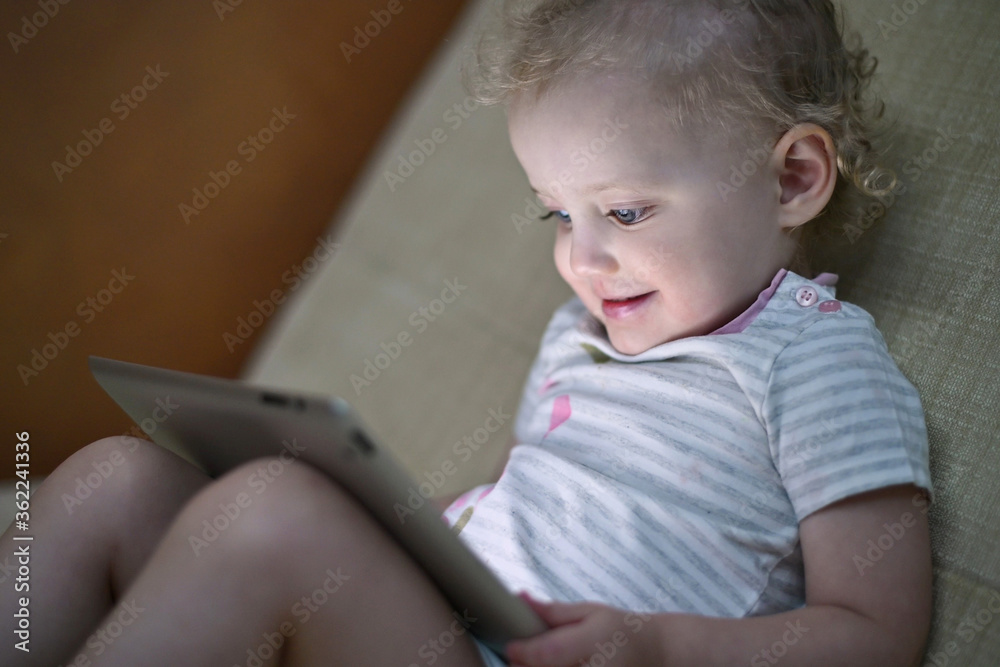 The child enthusiastically watches cartoons on the tablet, side view The child enthusiastically watches cartoons on the tablet, side view