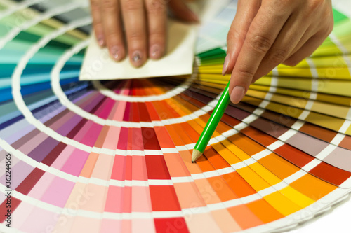 The hand of the designer shows a color palette. Catalog of rainbow color samples.

