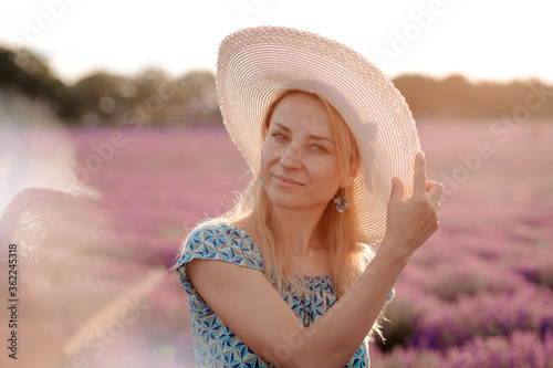 Beautiful woman in a hat walking in a lavender field
