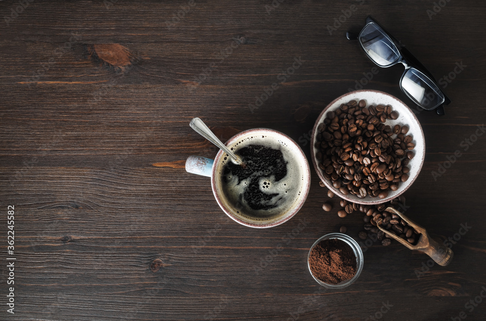 Photo of coffee Ingredients. Coffee cup, coffee beans, ground powder and glasses on wooden background. Copy space for your text. Top view. Flat lay.