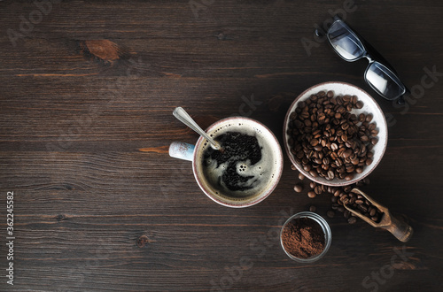 Photo of coffee Ingredients. Coffee cup, coffee beans, ground powder and glasses on wooden background. Copy space for your text. Top view. Flat lay.