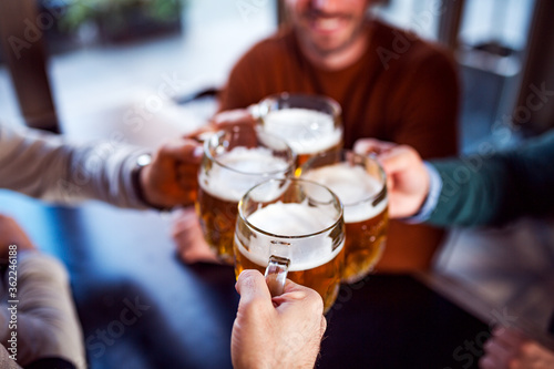 Friends clinking glasses with beer in beer pub