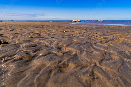 A structure made of wet sand with a reflection of the sun on the beach close-up with space for text. Background of sand in sunlight.