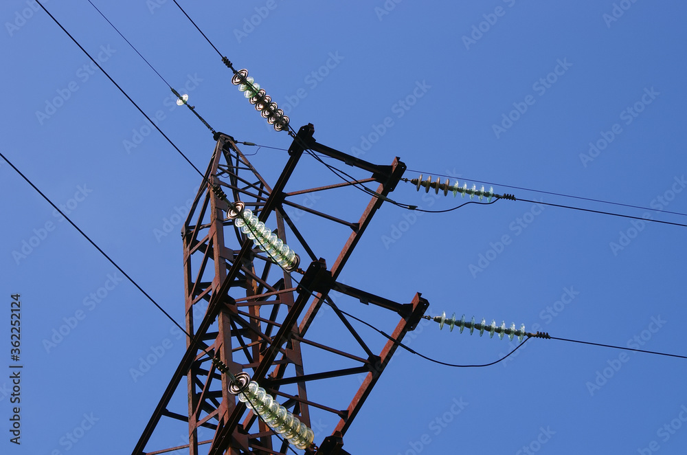 Electricity pylon with insulators and power lines. Blue sky background. Rusty weathered metal
Electricity pylon with insulators and power lines. Blue sky background. Rusty weathered metal