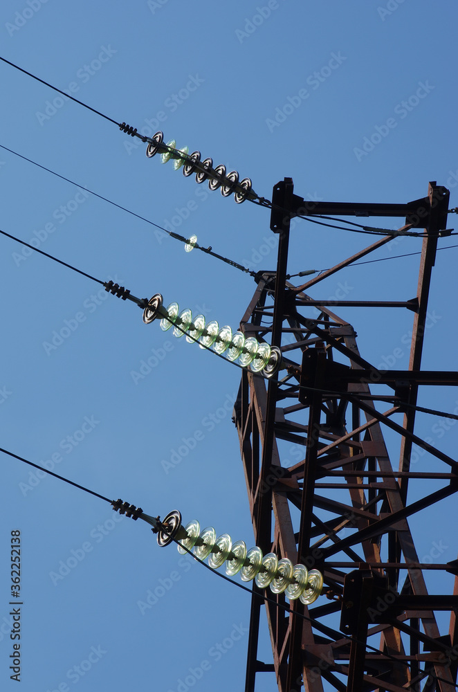 Electricity pylon with insulators and power lines. Blue sky background. Rusty weathered metal
Electricity pylon with insulators and power lines. Blue sky background. Rusty weathered metal