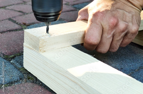 drilling in wooden boards. A hand holding a wood board