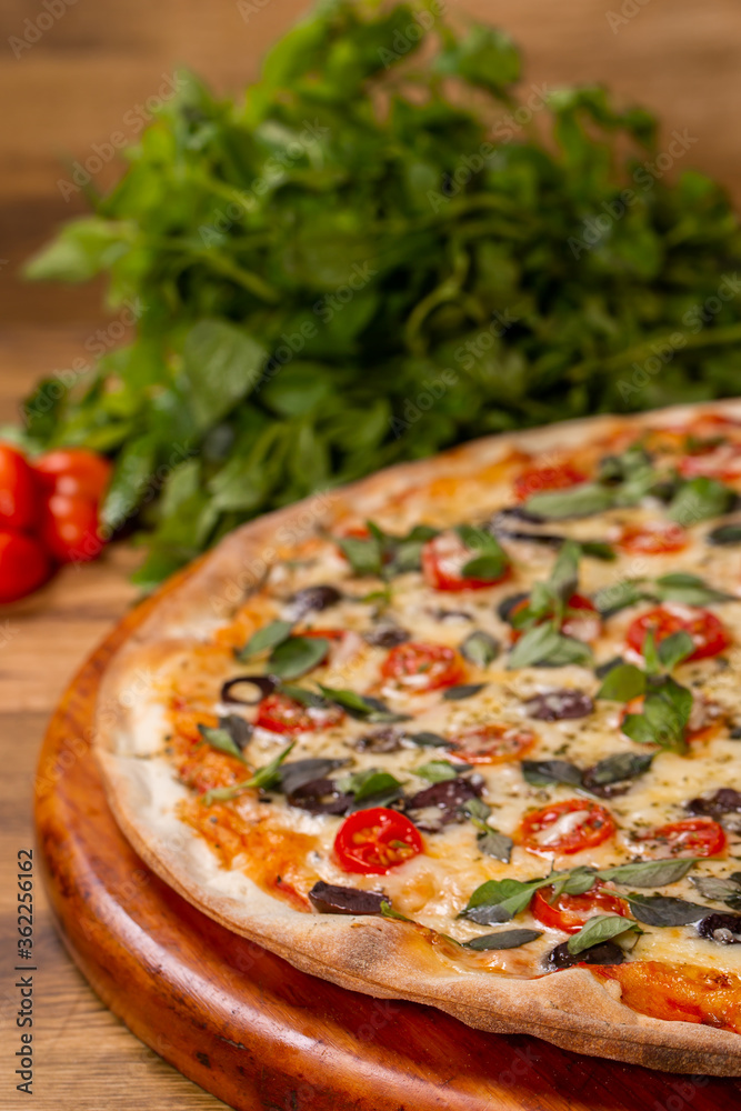 Cherry tomato pizza, black olive and basil on wooden background