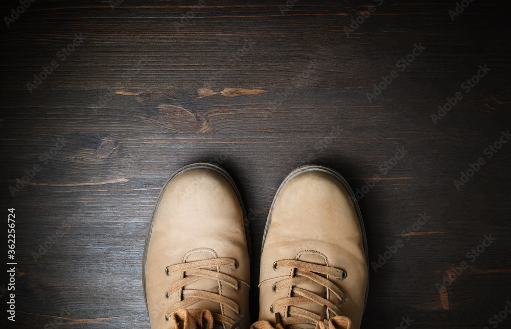 Shoes for travel. Travel boots on brown wood floor background. Copy space for your text. Flat lay.