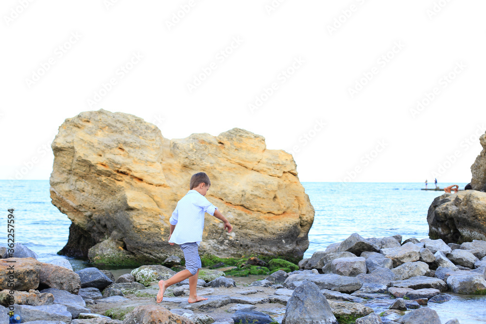 A child on the stones near the sea in summer.