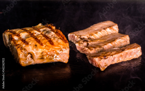 delicious pieces of salmon fillet that cook on a hot iron plate with smoke coming out