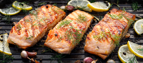 Foto Grilled salmon fillets sprinkled with fresh herbs on a grill plate close up