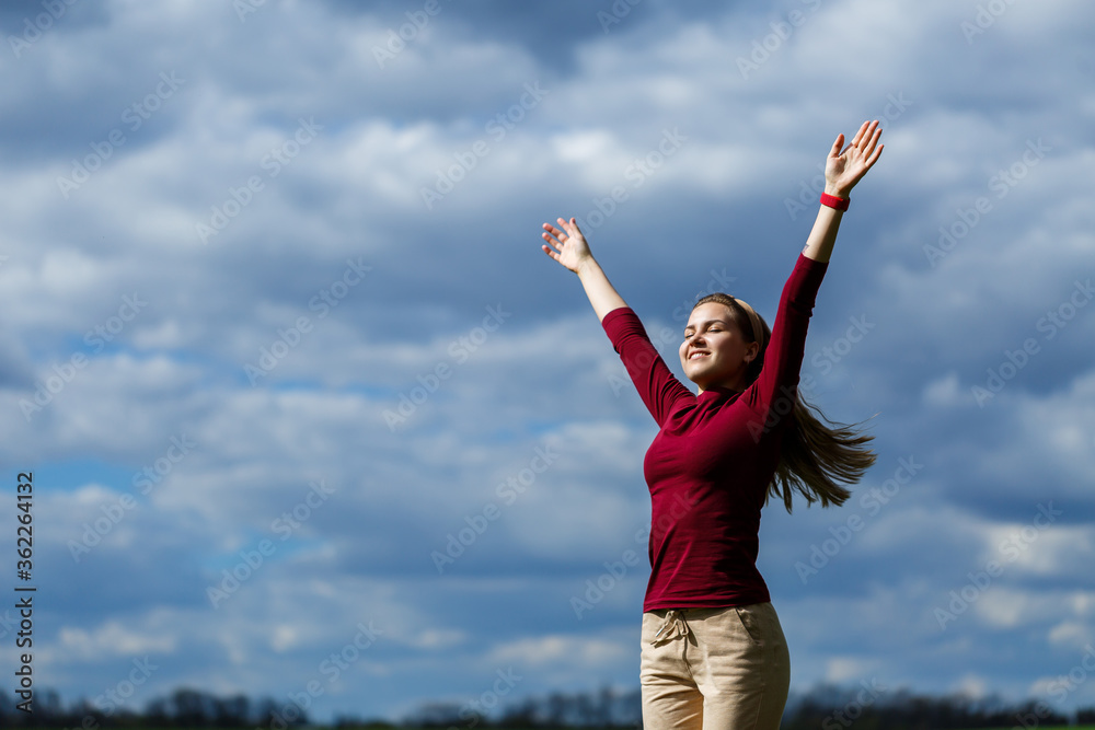 Joyful young girl on a background of the sky with clouds. He raised his hands up and laughed. Happiness in lifestyle. Inspiration in nature. Rest after a good working day. Joyful young girl on a background of the sky with clouds. He raised his hands up and laughed. Happiness in lifestyle. Inspiration in nature. Rest after a good working day.
