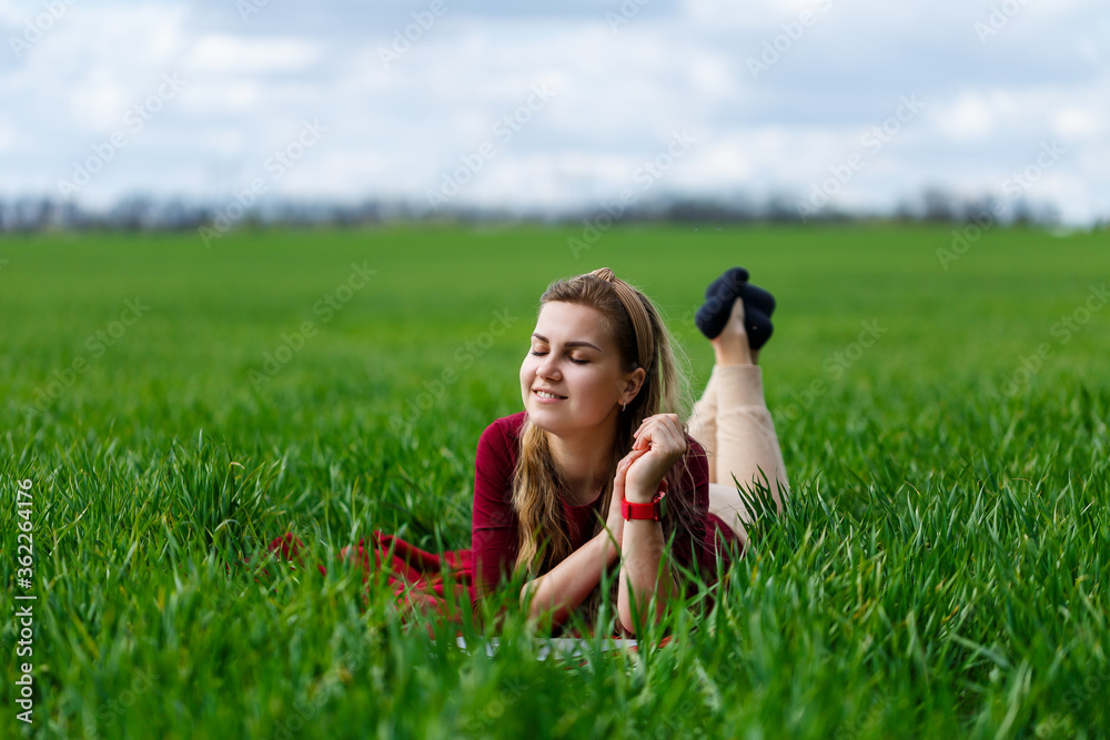 Young beautiful woman student with a laptop lies on the grass. Work outdoors. Young beautiful woman student with a laptop lies on the grass. Work outdoors.