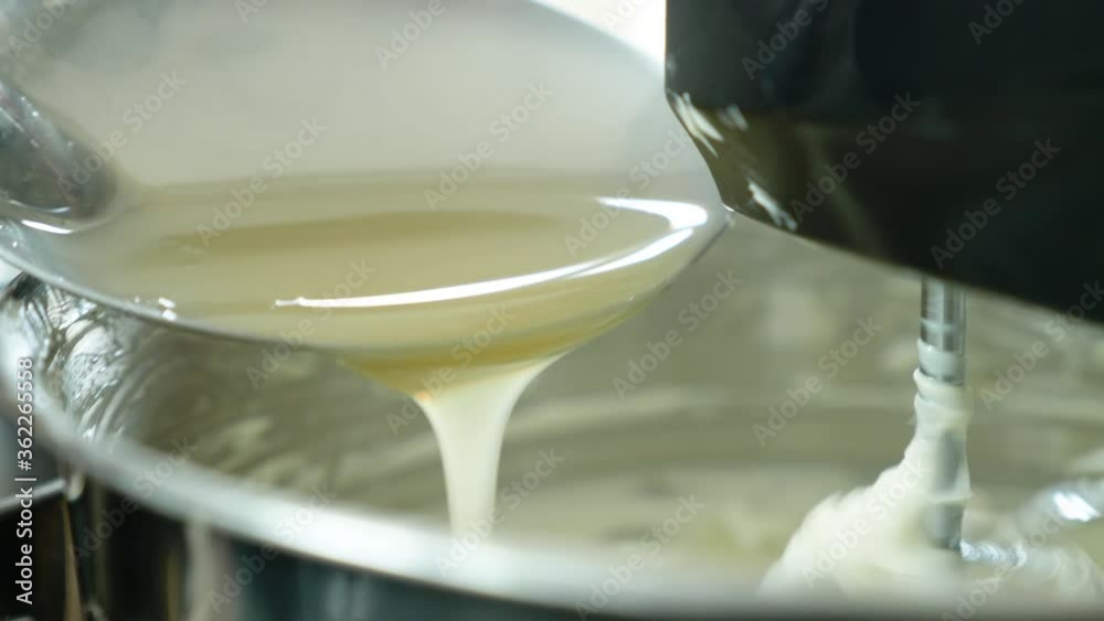 Closeup of stand mixer mixing delicious cream to make cake. ingredient of cake is egg, whites, butter and sugar in the bowl of mixer machine. automatic flour mixing machine is easy prepare of dough.