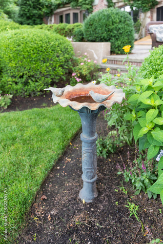 Vintage birdbath with two metal birds in a formal garden at an elegant home.