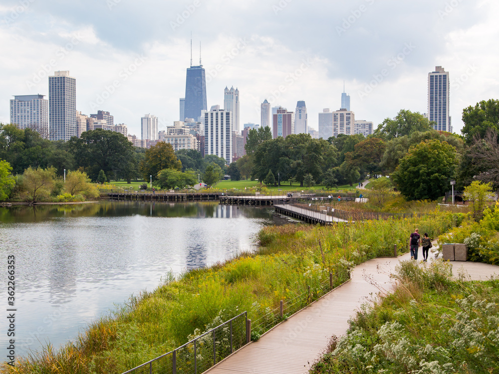 Lincoln Park in autumn foliage with people walking in alleys and city skyline in the background, Chicago, Illinois