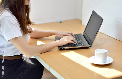 Closeup of Young Woman using a computer, Hand held mouse and keyboard, On a clean desk.