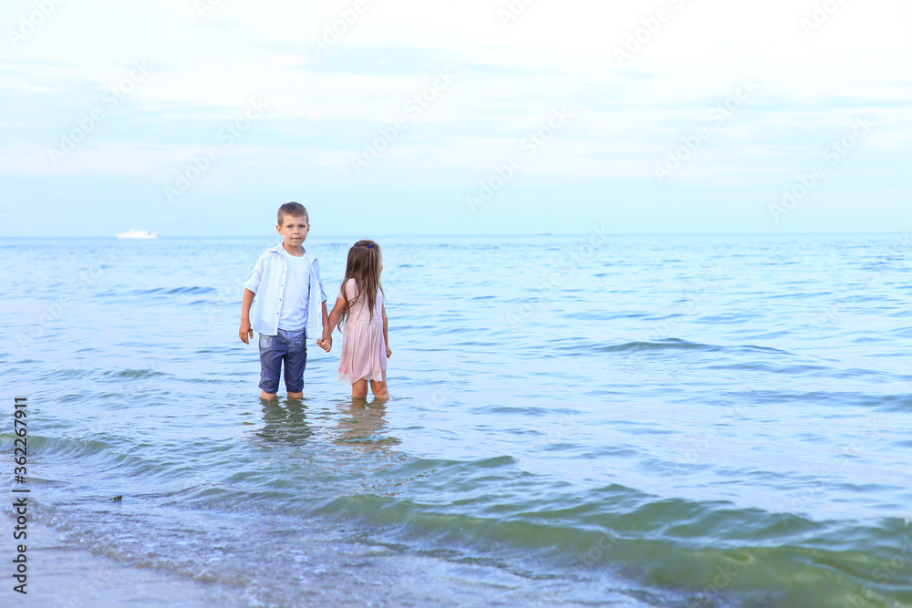 Two children run along the sea near the shore