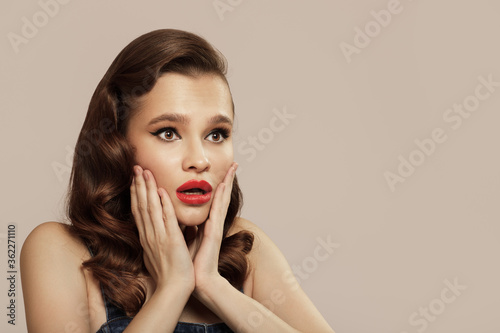 Portrait of beautiful surprised pin-up girl on gray background.