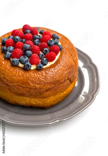 Savarin cake, a kind of rum baba, with custard cream and fresh berries. Isolated on white background.